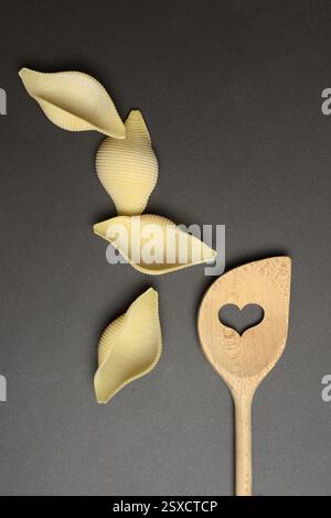 Conchiglione with wooden spoon, Italian pasta variety against a dark background, Italy, Europe Stock Photo