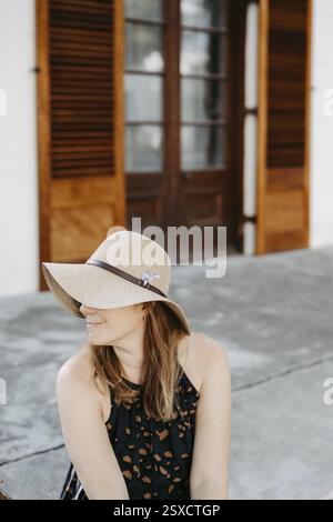 Woman with sunglasses and sun hat sitting on stone steps Stock Photo