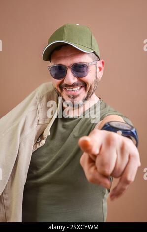 Happy man wearing casual clothes pointing finger at camera and smiling against brown background Stock Photo