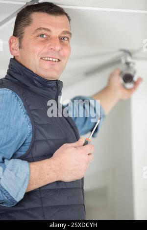 handyman installing security camera on the ceiling Stock Photo
