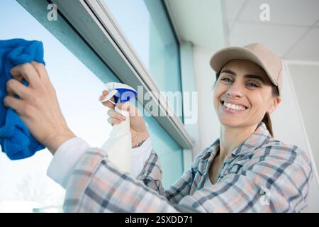 smiling professional woman cleaning windows Stock Photo