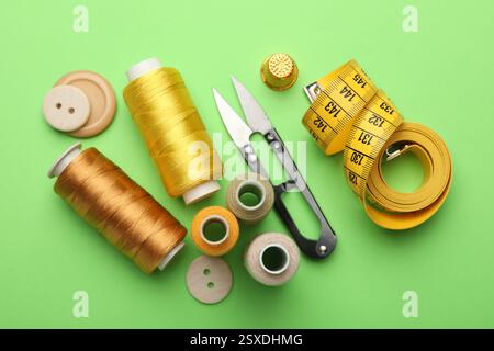 Different sewing supplies on green background, flat lay Stock Photo