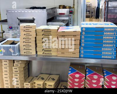 Stacks of pizza boxes ready for delivery in a bustling restaurant kitchen Stock Photo
