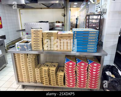 Stacks of pizza boxes waiting for delivery in a busy kitchen Stock Photo