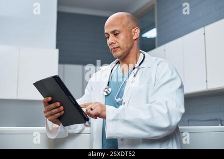 Professional Doctor in Lab Coat Using a Tablet Device in a Medical Office Stock Photo