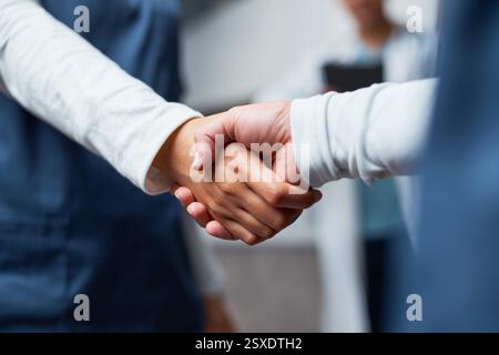 Close-Up of Handshake Between Medical Professionals Wearing Scrubs in a Teamwork and Collaborative Environment Stock Photo