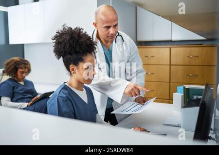 Medical Professionals Collaborating on Patient Records in a Modern Healthcare Setting Stock Photo