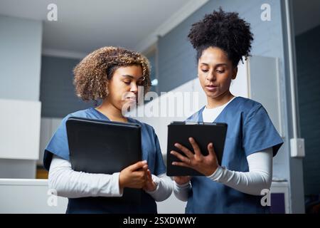 Two Healthcare Professionals Collaboratively Discussing Patient Information Using Tablet Devices in a Clinical Setting Stock Photo