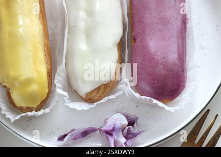 Three eclairs with different fillings lie in a plate Stock Photo