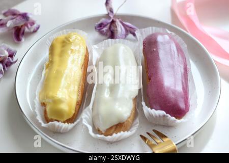 Three eclairs with different fillings lie in a plate Stock Photo