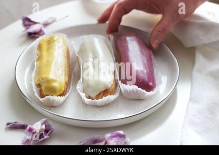 Three eclairs with different fillings lie in a plate Stock Photo