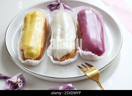 Three eclairs with different fillings lie in a plate Stock Photo