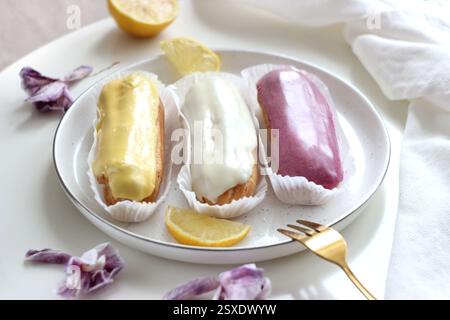 Three eclairs with different fillings lie in a plate Stock Photo