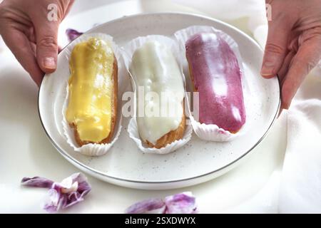 Three eclairs with different fillings lie in a plate Stock Photo