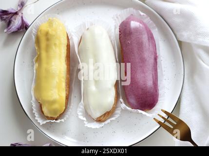 Three eclairs with different fillings lie in a plate Stock Photo