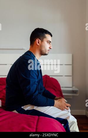 Young man playing video games sitting on bed at home Stock Photo
