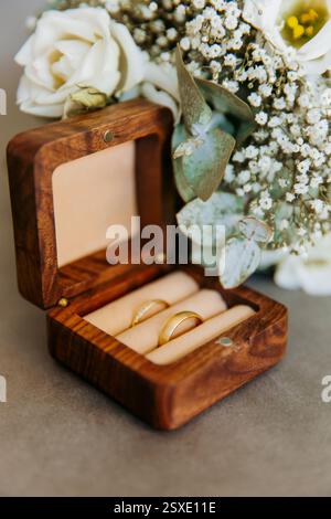Close up of an open wooden weeding ring box with golden rings and a bride bouquet Stock Photo