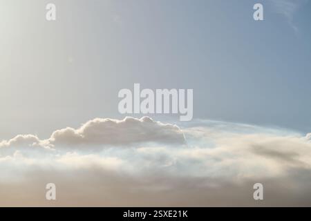 Sunlight shining through white clouds in blue sky Stock Photo