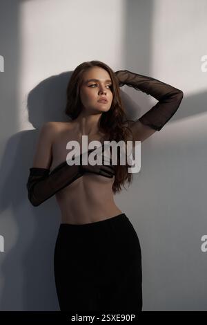model stands gracefully in an elegant pose, showcasing her outfit while striking a captivating expression. soft light casts gentle shadows, enhancing Stock Photo