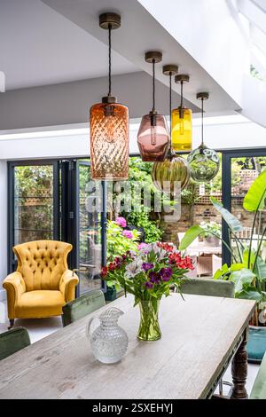 Five handblown glass lampshades above flowers and jug on table in West London home. London, UK. Stock Photo