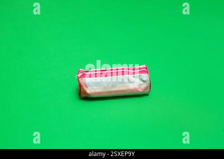 Closed pencil case lying on a vibrant green surface, ready for school or office use Stock Photo