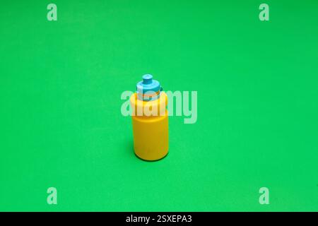 Yellow plastic water bottle with blue cap on green background, promoting hydration and an active lifestyle Stock Photo