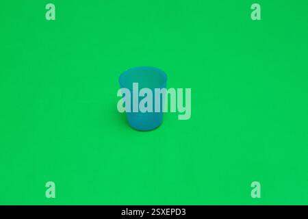 Studio shot of a small, textured, light blue plastic cup on a vibrant green backdrop Stock Photo