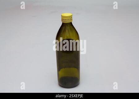 Empty dark green glass bottle with yellow cap standing on a white background Stock Photo