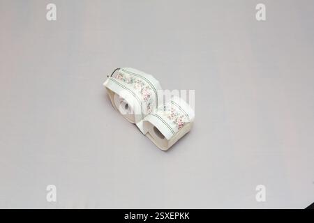 Two rolls of toilet paper covered with floral fabric sit on a table, adding a touch of elegance to a bathroom essential Stock Photo