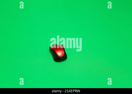 Red and black wireless mouse placed on a bright green background, ideal for technology or communication concepts Stock Photo