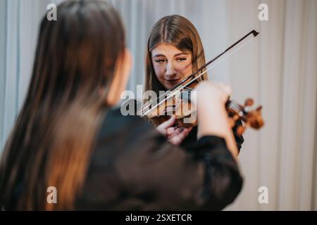 Two musicians practicing violin together in a focused and emotional setting Stock Photo