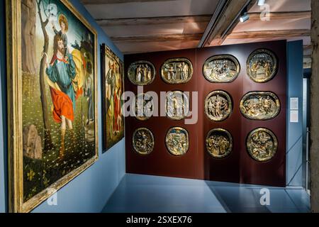 Twelve round reliefs depicting biblical scenes hang in rows on an exhibition wall in the Pfalzmuseum in Forchheim, beside two framed panel paintings showing figures of saints. The museum is housed in the Kaiserpfalz, built in the late 14th century for the Bamberg prince-bishop Lambert von Brunn. Sattlertorstraße, Forchheim, Bavaria, Germany. Stock Photo