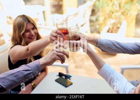 A diverse group of friends sitting together in a cozy cafe, smiling and raising their glasses in a joyful toast, celebrating friendship and good times Stock Photo