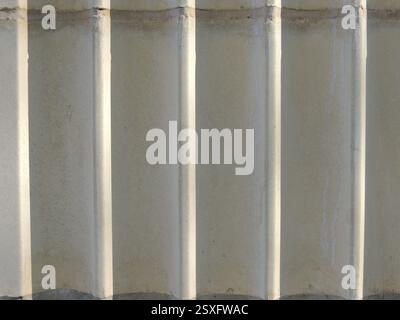 gray ribbed textured background with vertical stripes, fragment of architectural structure with volumetric highlighted stripes Stock Photo