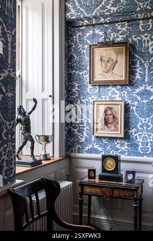 Family portraits on blue 'Pomegranate Grand' wallpaper in Bayfield Hall, an 18th century historic country house in Norfolk, UK. Stock Photo