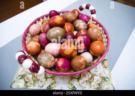 A bag filled with colorful Easter eggs naturally dyed with botanical leaf patterns, placed in a decorative vase. A unique and rustic holiday compositi Stock Photo