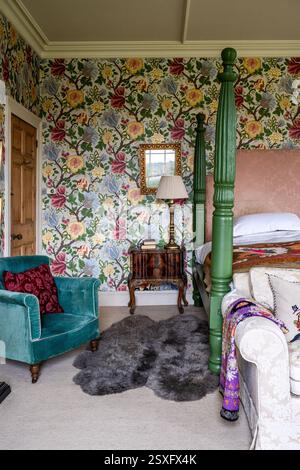 'Midsummer Bloom' wallpaper with teal armchair in master bedroom at Bayfield Hall, an 18th century country house in Norfolk, UK. Stock Photo