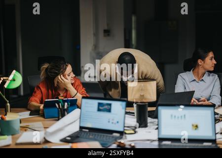 Two colleagues engage in a late-night discussion at the office, collaborating on business strategies. Stock Photo