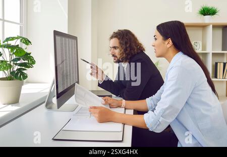 Two young accountants working with business spreadsheets on their office computer Stock Photo