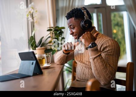 Freelancer using digital tablet to communicate online. He is sitting in bar and having video call. Stock Photo