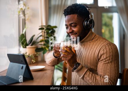 Freelancer using digital and having video call in bar. He is drinking tea. Stock Photo