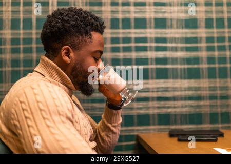 Young black man enjoying hot chocolate in bar. Portrait of man who is drinking hot chocolate. Stock Photo