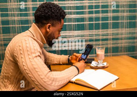 Freelancer using smartphone and notepad. He is sitting in bar and making plans for work. Stock Photo