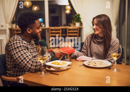 Two friends are having dinner at restaurant. They are exchanging gifts. Stock Photo