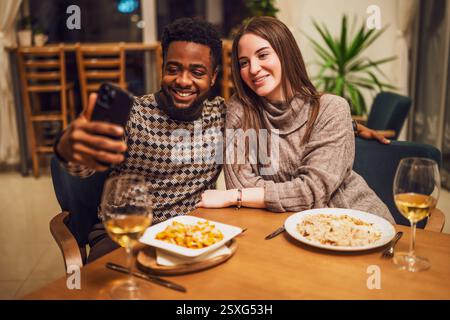 Two friends are having dinner at restaurant. They are taking selfie. Stock Photo