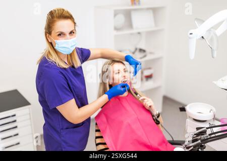 Dentist examining a patient in a dental clinic. Happy dentist at work, she is looking at camera. Stock Photo