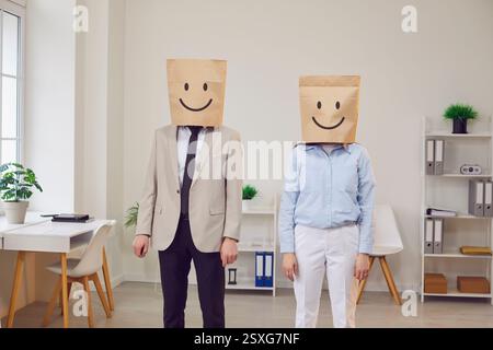 Happy employees office managers workers standing wearing paper bag with funny smile face having fun Stock Photo
