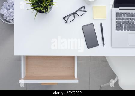 Tidy clean minimalistic office desktop with laptop, personal items and open empty drawer, top view Stock Photo