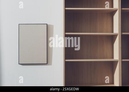 Home interior with empty wooden bookcases and blank framed picture hanging on the wall Stock Photo