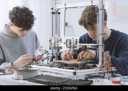 Young students working together in the lab, they are learning how to use a 3D printer: education and technology concept Stock Photo